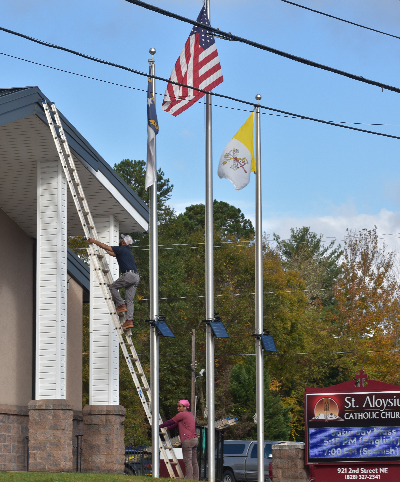 Chancellor Freddie Garcia climbing the ladder to perform repairs on St. Aloysius church.